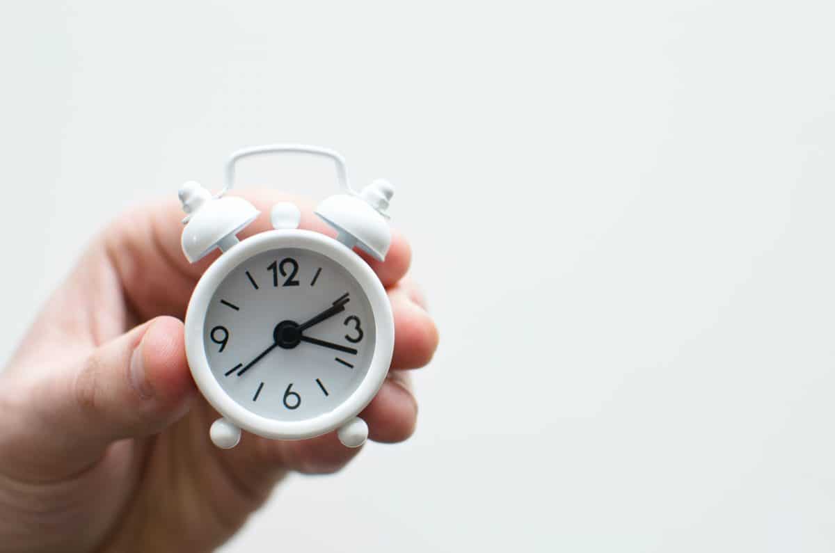 person holding white mini bell alarmclock